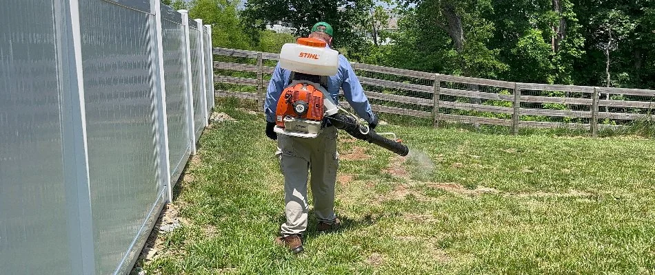 Professional in Gallatin, TN, applying a tick control treatment to a lawn.