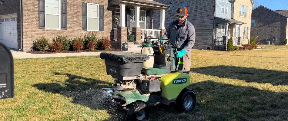 Worker in Gallatin, TN applying granular lawn fertilizer.
